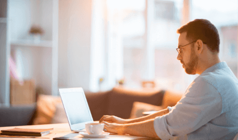 A school bursar working from home on a desk with laptop and coffee