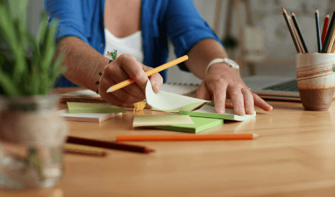 A woman peeling off a new post it note placed on the desk