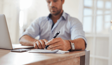 Man making notes next to laptop